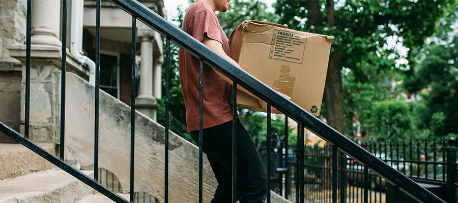 Student walking down the stairs carrying moving box